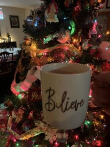My white coffee cup with a gold handle, inscribed with the word Believe